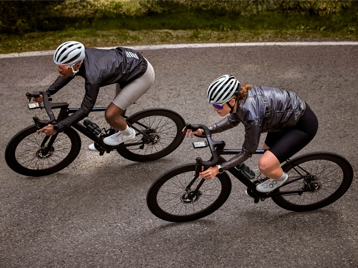 A closeup aerial shot of two riders going down a road, each with a Garmin 1060 mounted to their handlebars.