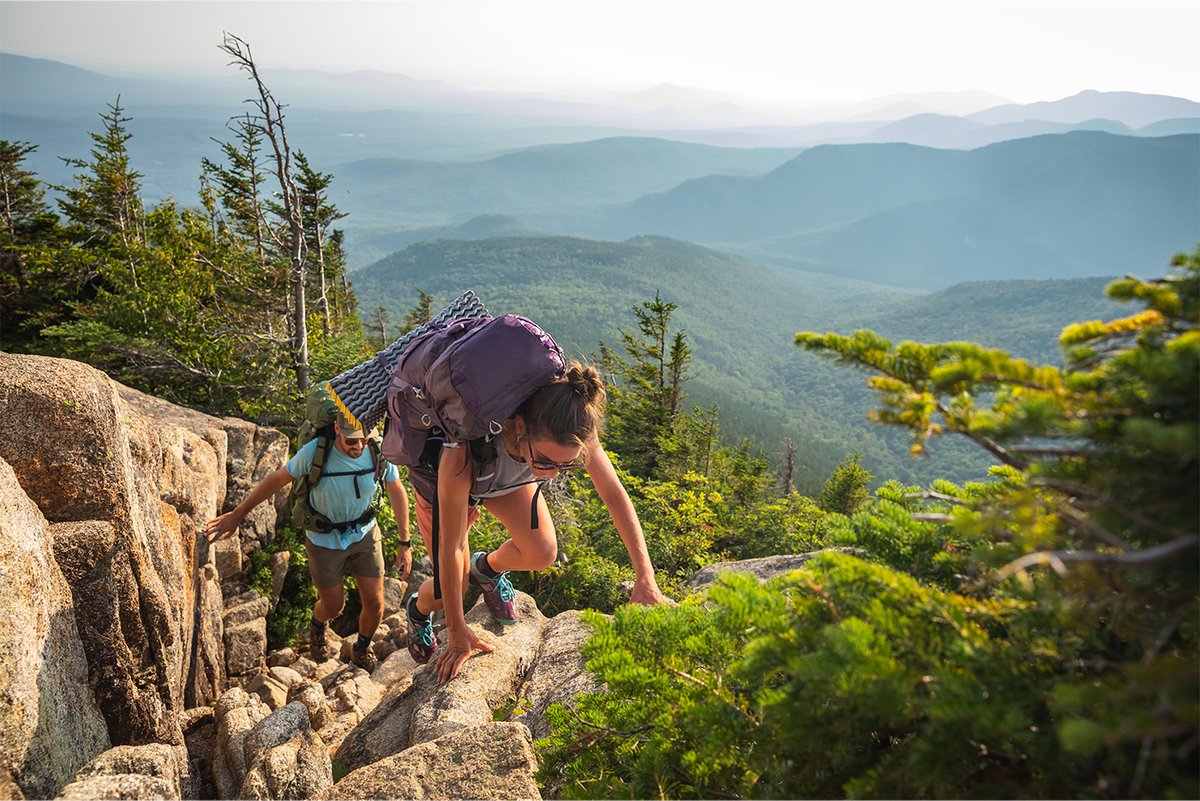 Two backpackers scramble up a rocky incline