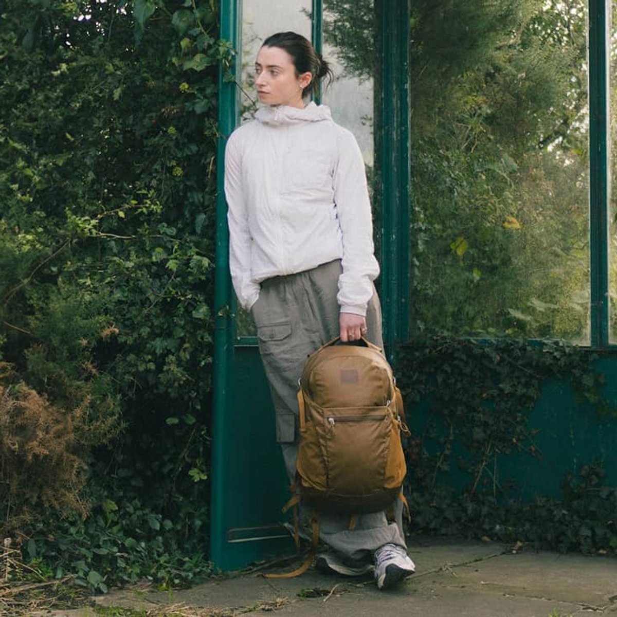 A woman leans against a wall, holding an Osprey Limited Edition bag. 