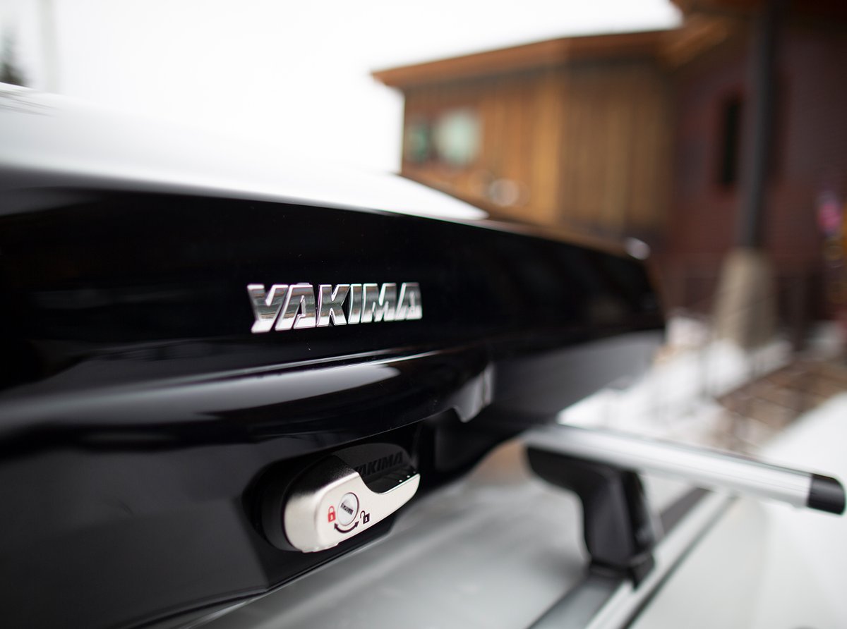 Close-up of Yakima GrandTour rooftop cargo box with lock on vehicle roof rack in snowy setting
