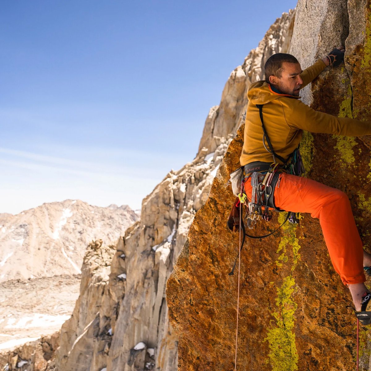 A man wearing the Patagonia R1 Ultralight climbs a rocky cliff face.