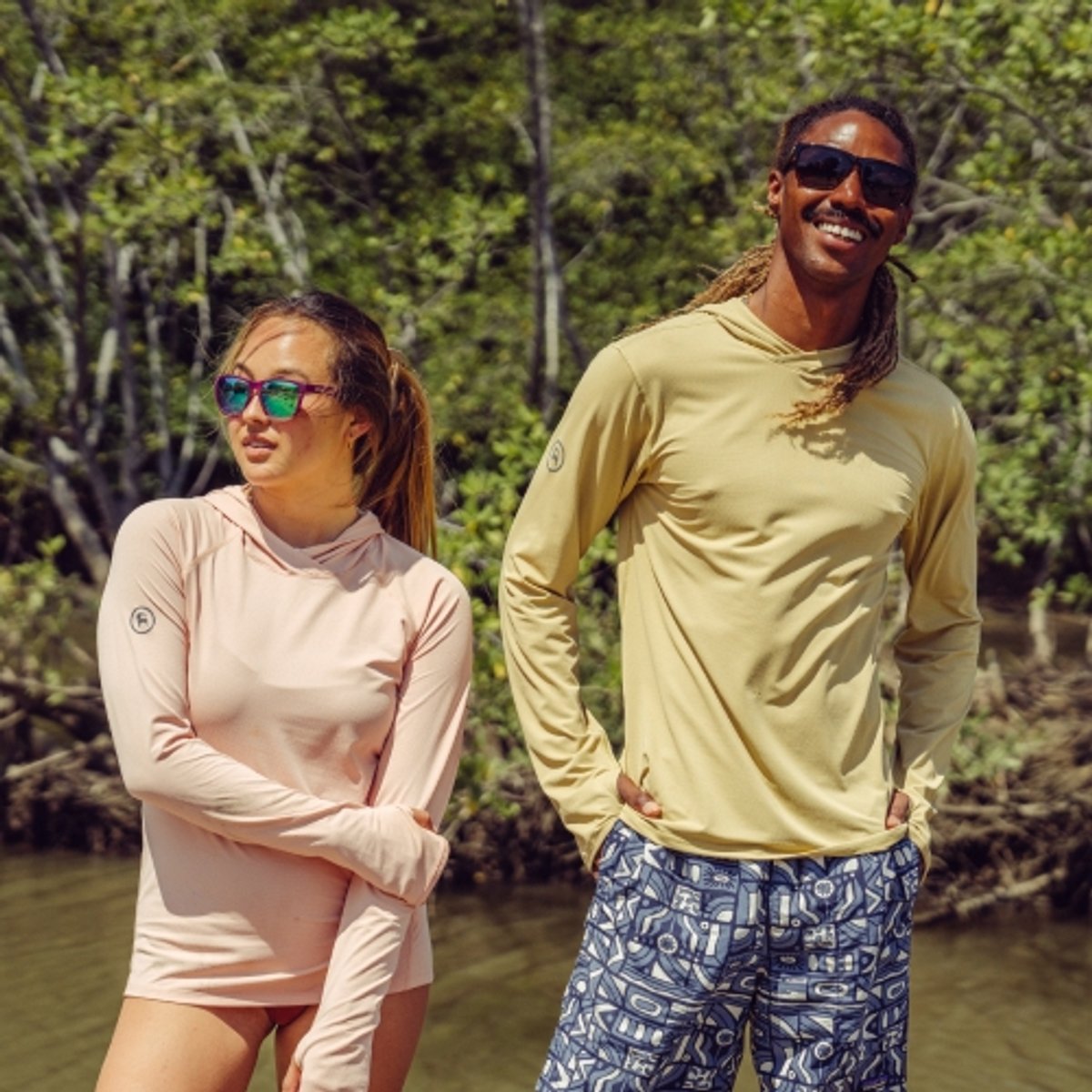 Two hikers enjoy the sunshine while wearing their Backcountry Tahoe Sun Hoodies. 