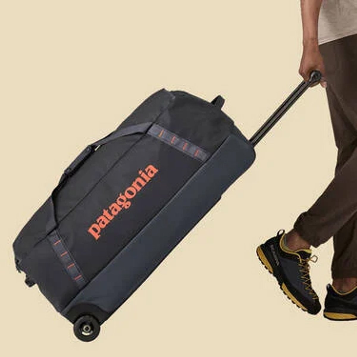 A person pulling a Black Hole Wheeled Duffel 100L behind them.