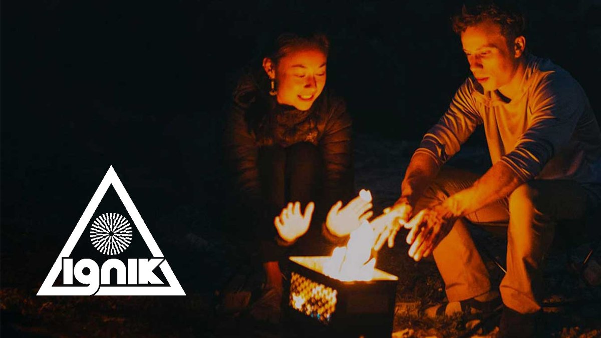 Two people warming their hands over a glowing campfire at night with the Ignik logo displayed.