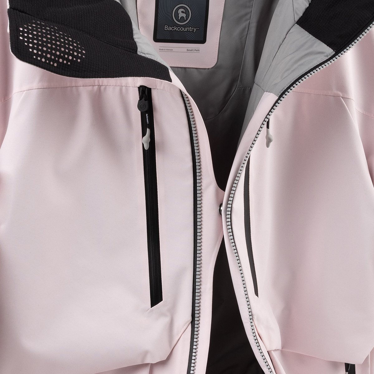 Close-up of an unzipped light pink Cottonwoods jacket, showing the center front snap that has been fastened.