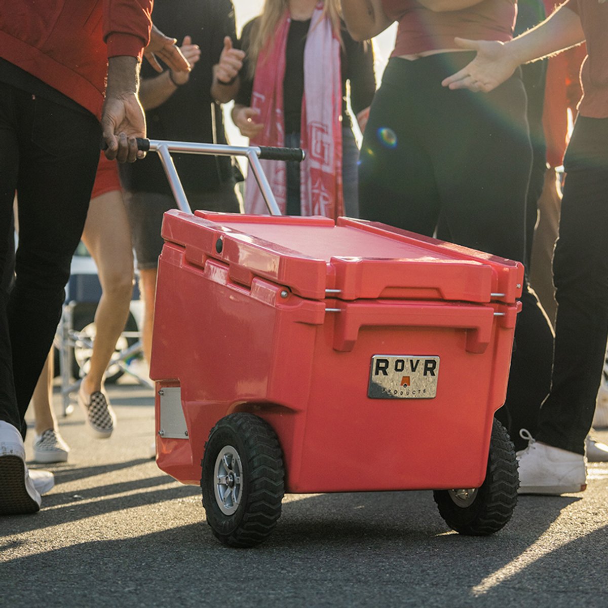 RovR RollR wheeled cooler being pulled by its handle through a crowd at an outdoor event.