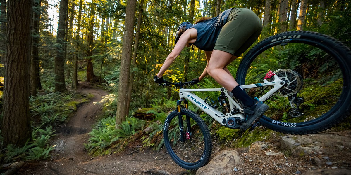 A downhill mountain biker does a steep drop on an electric mountain bike.
