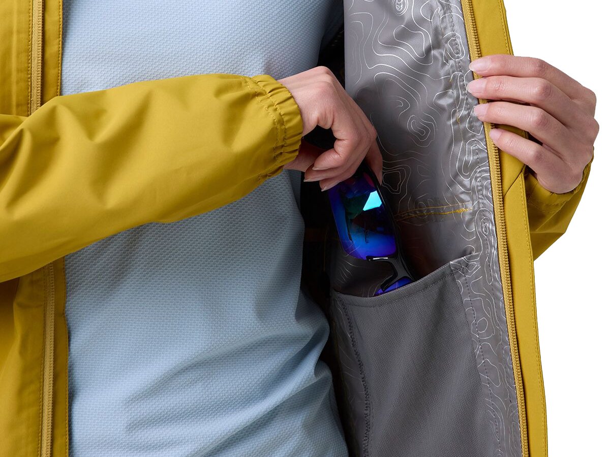 Close-up of yellow rain jacket interior goggle pocket with ski goggles being stored inside topo-print lining